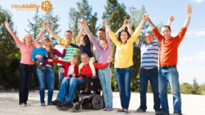 Group of people in various bright colored shirts including one man in the center in a wheelchair and a child in the center. 