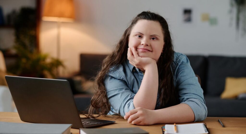 Woman with downs syndrome sitting at a desk with a laptop in front of her