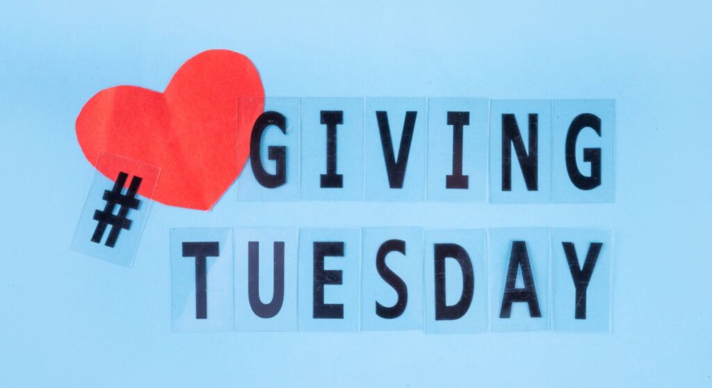Blue background with black text saying "Giving Tuesday." There's a red heart and a black # symbol to the left.